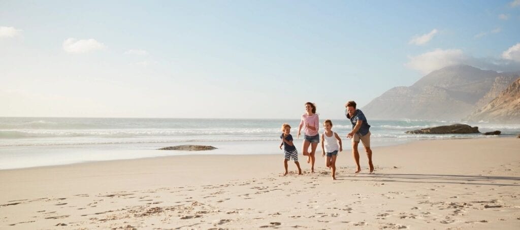A family of four walking on the beach.