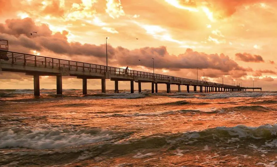 A pier with people walking on it at sunset.