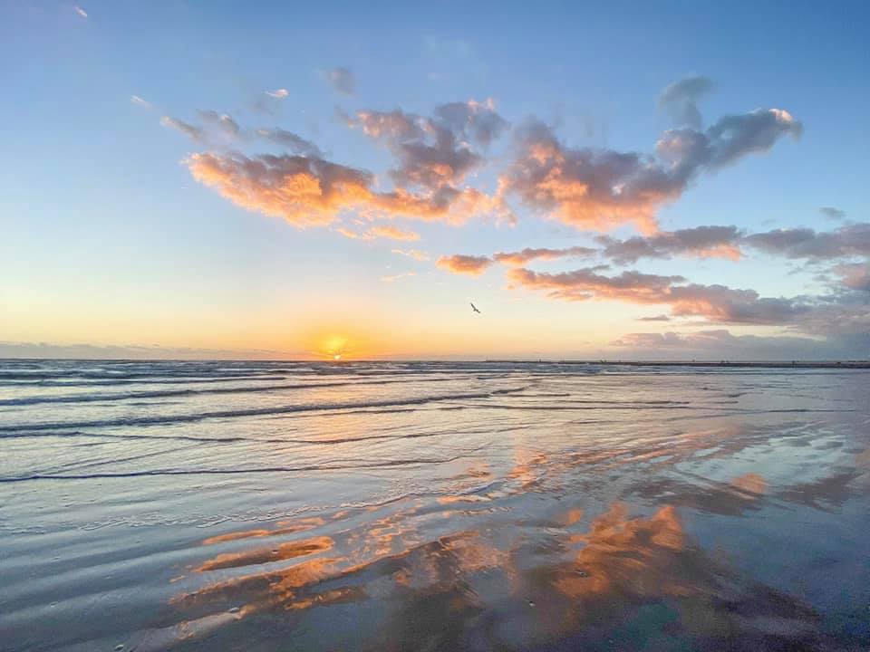 A beach with the sun setting in the background.