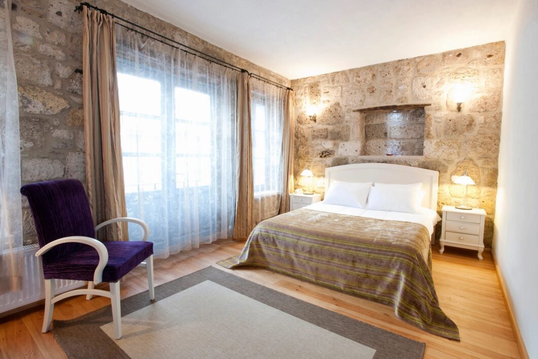 A bedroom with a bed, chair and window.