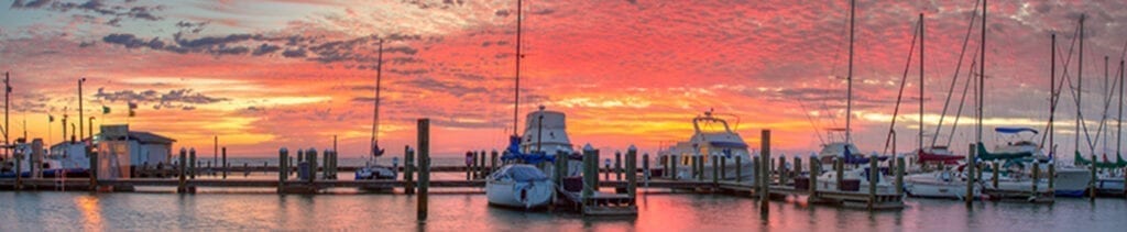A boat is docked in the water at sunset.