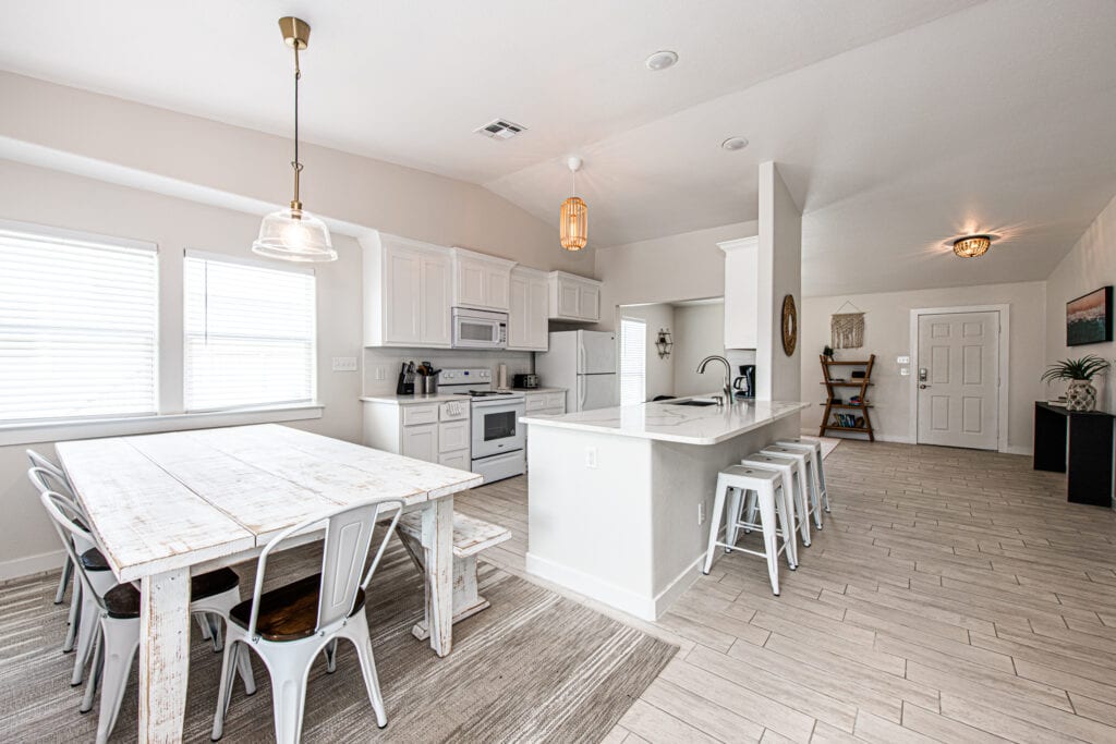 A large white kitchen with an island in the middle.