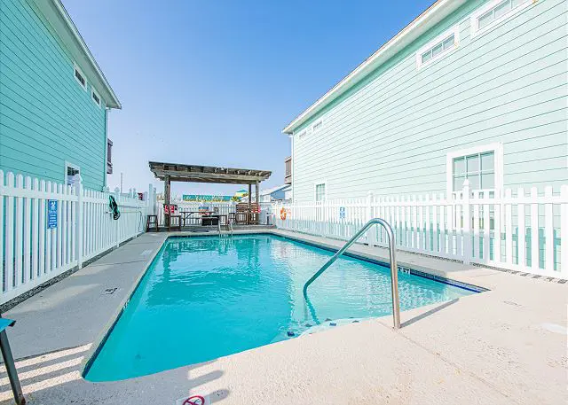 A pool with a pergola and steps leading to it.