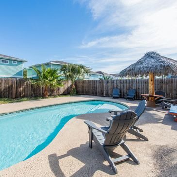 A pool with chairs and an umbrella next to it.